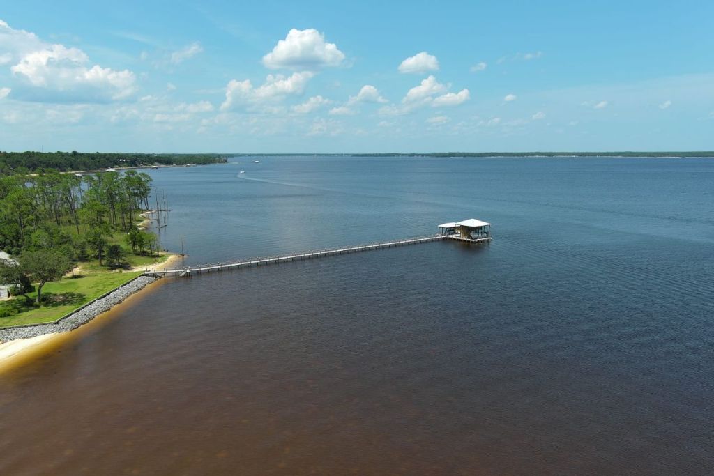 Aerial view of a long wooden pier extending into a calm blue lake