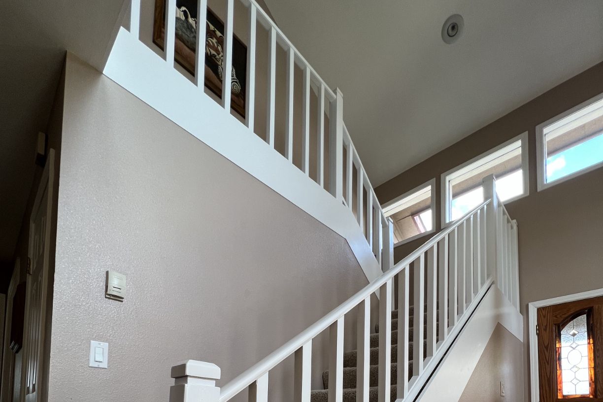 View of staircase with white railing and windows above