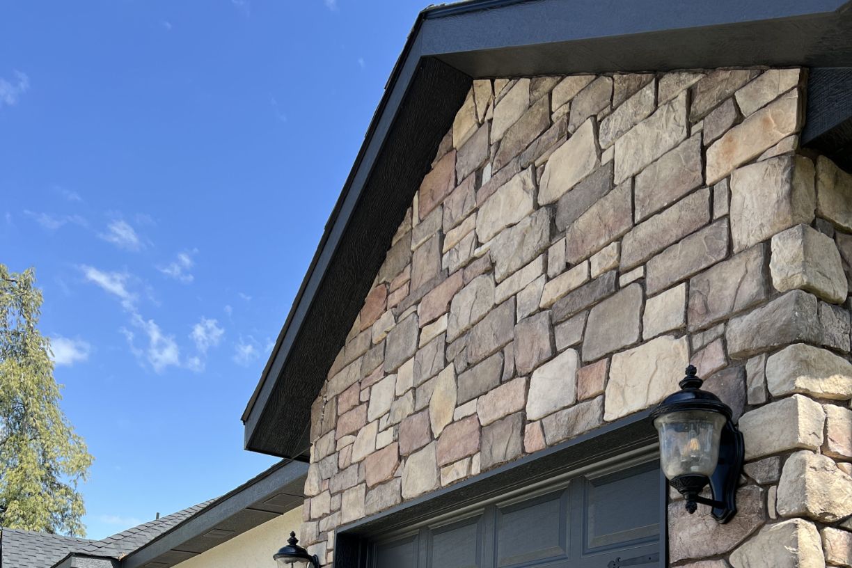 Close-up of stone wall with garage lights and clear blue sky