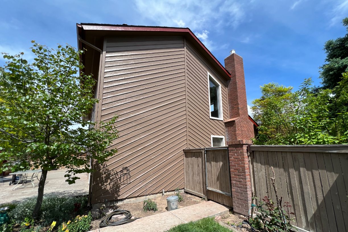 Side view of house with fenced yard and chimney