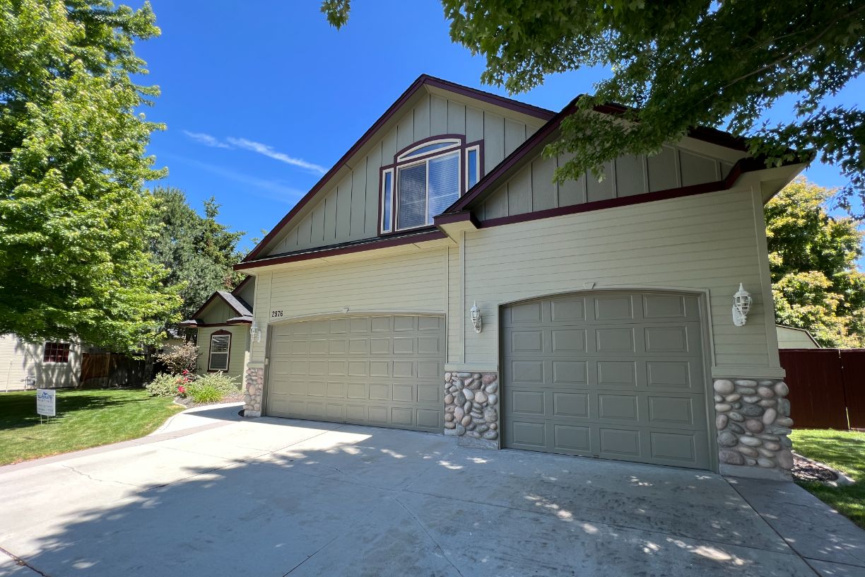 Two-car garage with stone accents and greenery