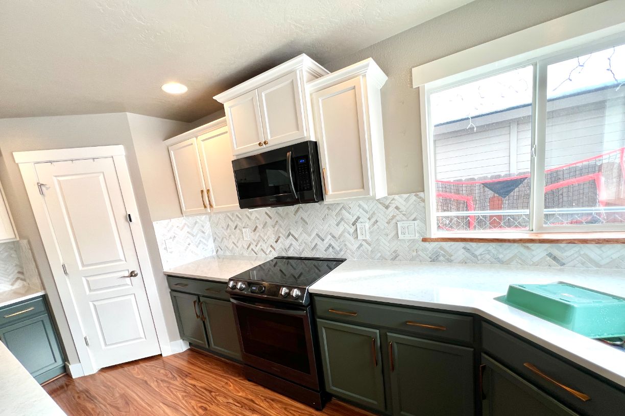 Modern kitchen with green cabinets, white countertops, and microwave