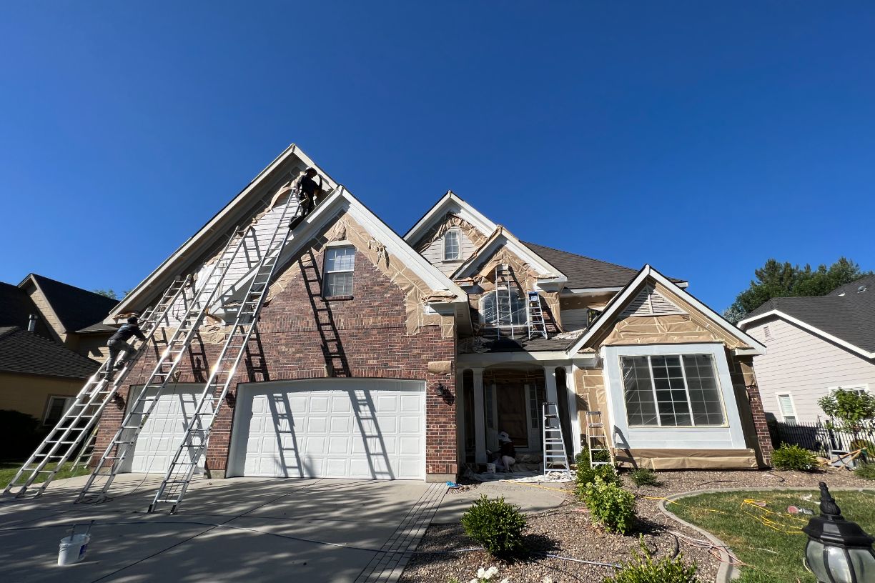 Workers painting exterior of brick house