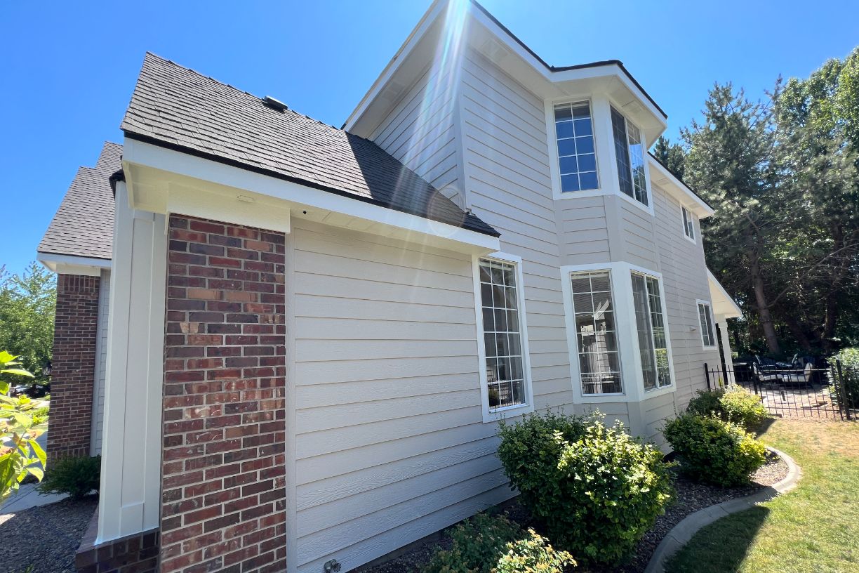 Light-tan siding, brick accents, sunny yard