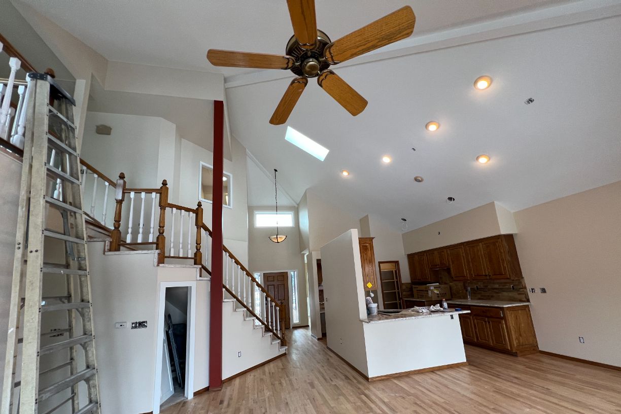Living room with staircase, ceiling fan, and wooden floor under renovation