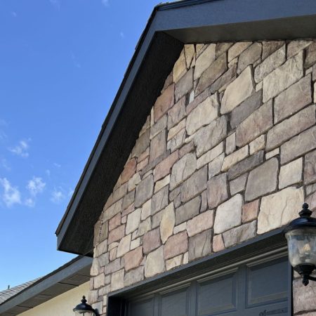 Close-up of stone wall with garage lights and clear blue sky
